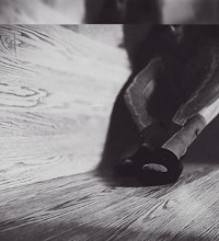 a black and white photo of a person sitting on a wooden floor